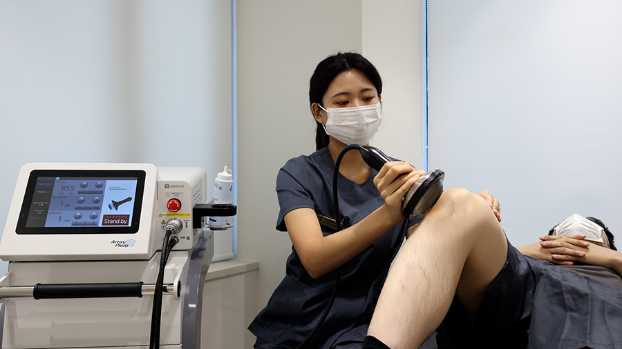 치료사가 환자의 무릎에 체외충격파 치료를 시행하는 모습